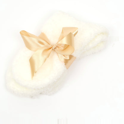 Cream fuzzy socks tied with a gold satin bow