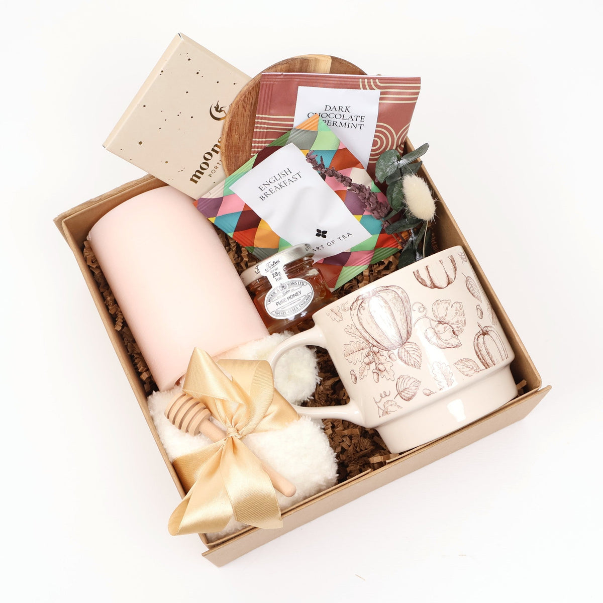 Cozy fall tea gift box with a pumpkin print mug, blush pillar candle, fuzzy socks, and honey in a kraft box
