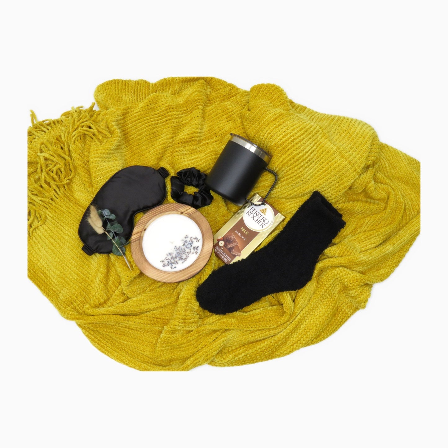Gift box contents arranged across a marigold chenille knit throw blanket