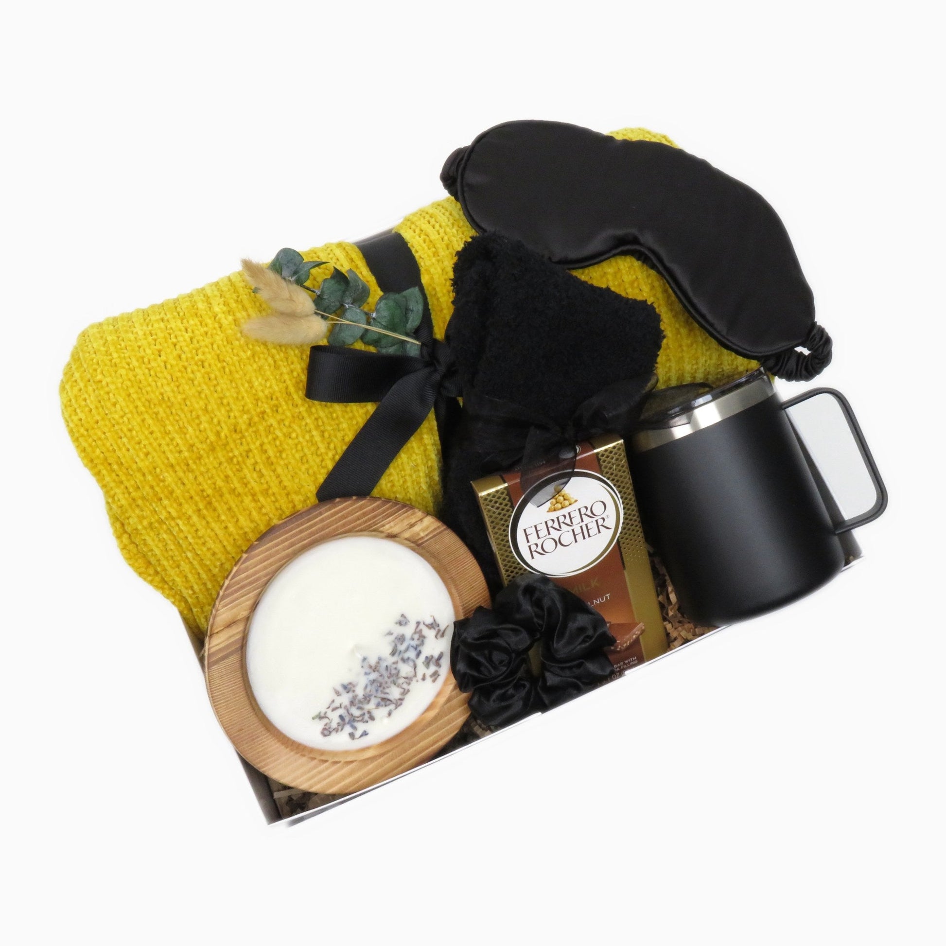 Cozy relaxation gift box with a yellow chenille knit throw, black satin sleep mask, insulated mug, and lavender soy candle