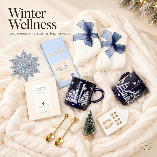 Cozy winter gift box with a plush throw, village mugs and an LED house, styled items